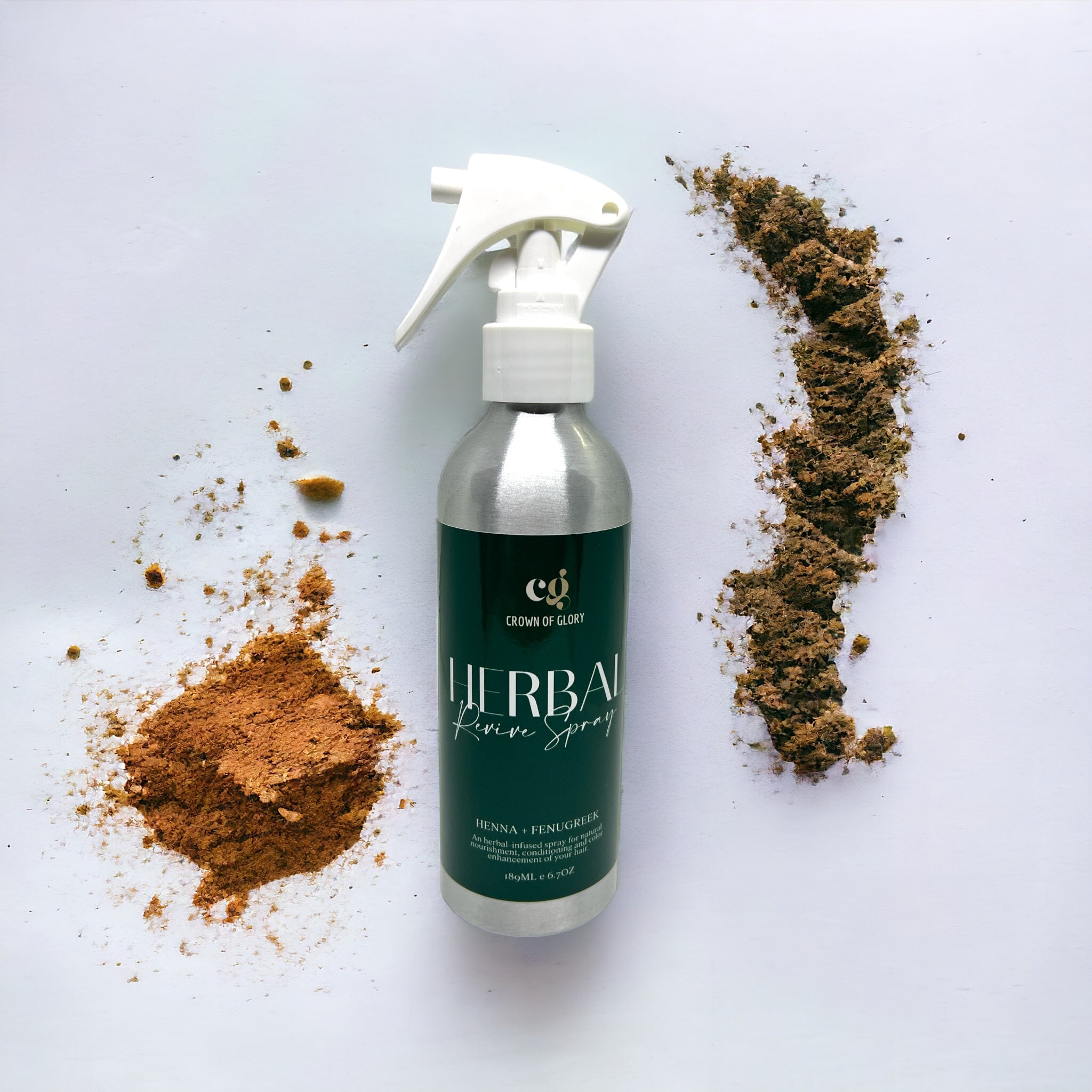 A silver bottle labeled "Herbal Revive Rinse" by Crown of Glory rests on a white background, capturing the spirit of Ayurvedic hair care. It is surrounded by two piles of brown powder, one with a more reddish hue, emphasizing its natural nourishment benefits for your hair.
